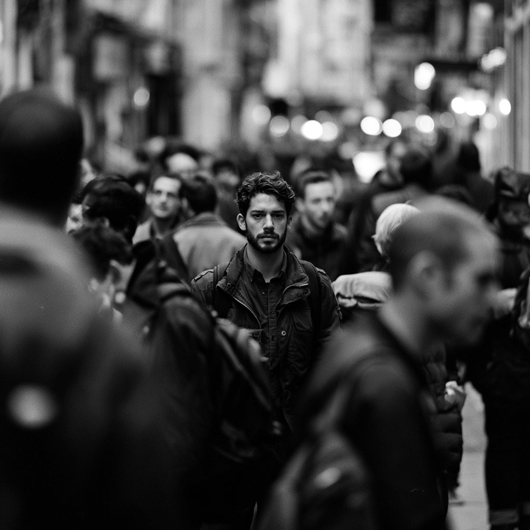 Black-and-white image of a man blending into a busy city crowd.